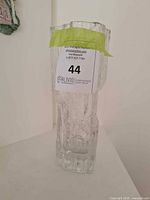 Front view of a clear glass vase with iceberg texture and auction sticker.