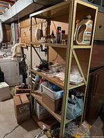 Full view of the metal storage shelf against a basement wall, holding various household items but only shelf included.