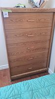 Front view of the oak tall boy dresser showing five drawers with wood handles.