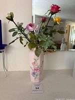 Full view of the tall hexagonal ceramic vase with artificial floral arrangement on top, showing the overall shape and decoration.