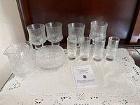 Overview of all glassware pieces arranged on doily-lined surface