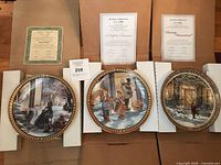 Three Trisha Romance collector plates displayed in protective frames with certificates of authenticity placed behind each plate on boxes.