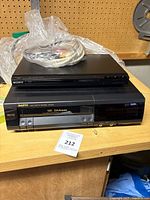 Front view of Sanyo VHS VCR and Sony DVD player stacked, showing Sanyo VHS D4 Head model label and AV cables on top.