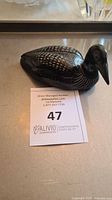 Black polished stone figurine carved in the shape of a loon bird, with painted white pattern details