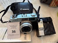 Canon vintage Canonet 28 camera with lens and Canon branded carrying case, flash unit, and additional black pouch case.