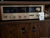 Front view of vintage Pioneer SX-424 stereo receiver showing knobs for speaker, bass, treble, volume, and buttons for speaker selection and output metering. Wood side panels and metal faceplate.