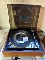 Front angle showing Dual 1214 turntable with open dust cover, tonearm, and platter mat inside wooden base.