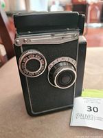 Front angled view showing black textured body, aperture and shutter speed dials.