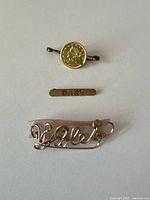 All three pins laid out: coin motif, BABY bar, Violet script