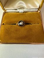 Top view of ring in box showing pearl and black inlay
