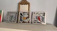 Mirror and three bird wall art pieces displayed on shelf