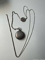 Pocket watch with attached chain and medallion laid out