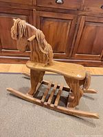 Full side view of wooden rocking horse on carpet
