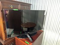 Front view of Samsung 40-inch TV on stand with remote