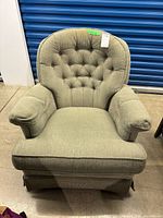 Front view of green-beige tufted swivel armchair