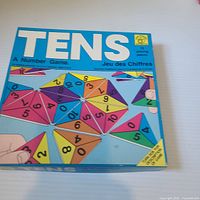 Front of Tens game box showing title and graphic triangular numbered pieces