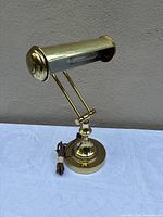 Front angled view of brass piano lamp showing overall design and cord