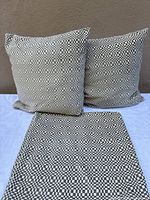 Two checkerboard cushions and one cover displayed