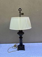 Full view of brass lamp with pleated shade and finial