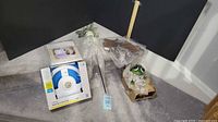 Group shot of all items including boxed sprinkler, frog statue, chair cover, decorative frame