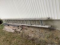 Full view of 24 ft aluminum extension ladder leaning against house exterior