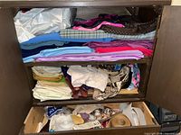 Cabinet with multiple shelves of folded fabric and bottom drawer containing sewing notions