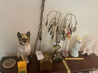 Overview of lot on tabletop showing lamp, cat figurine, owl figurine, glass dome shell, Galileo thermometer, coasters, wooden box