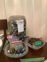Wide shot showing jar of marbles, tub of marbles, tub of keys