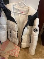 Front view of Reebok white and black insulated jacket on hanger with tags attached