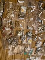 Multiple small zip bags containing assorted costume jewellery pieces on wood surface