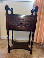Front view of wooden side table showing cupboard door and turned legs