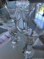 Four clear glass cordial glasses on glass table