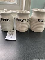 Front view of three labeled ceramic canisters with lids