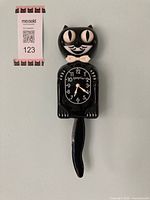 Front view of cat-shaped wall clock with pendulum tail attached