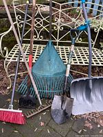 Group of six garden tools leaning against bench