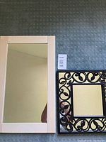 White rectangular mirror and black square scrollwork mirror side by side