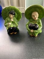 Front view of both green ceramic figurines displaying form and colour