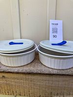 Two identical white Corning Ware casseroles with lids