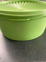 Side view of green round container showing embossed motif