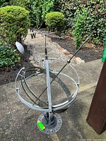 Full view of metal armillary sphere sundial and weather vane on base