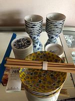 Group shot of stacked porcelain bowls, coasters, floral plates, chopsticks
