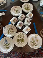 Overview of plates and mugs with botanical designs on table