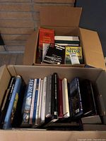 Two cardboard boxes filled with assorted books, some titles visible