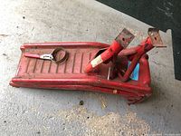 Two red metal ramps with jack stands and oil filter wrench stacked