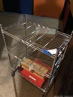 Full view of chrome wire shelving cart with three shelves and wheels