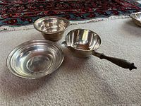 Two bowls and one ladle grouped on carpet