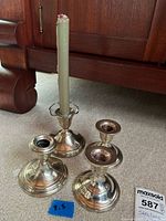 Four silver candle holders and candle overall view
