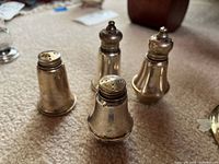 Group of four sterling shakers standing upright