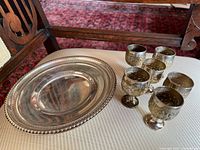 Shallow dish and six cups on upholstered surface