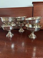 six small pedestal bowls grouped on wood surface